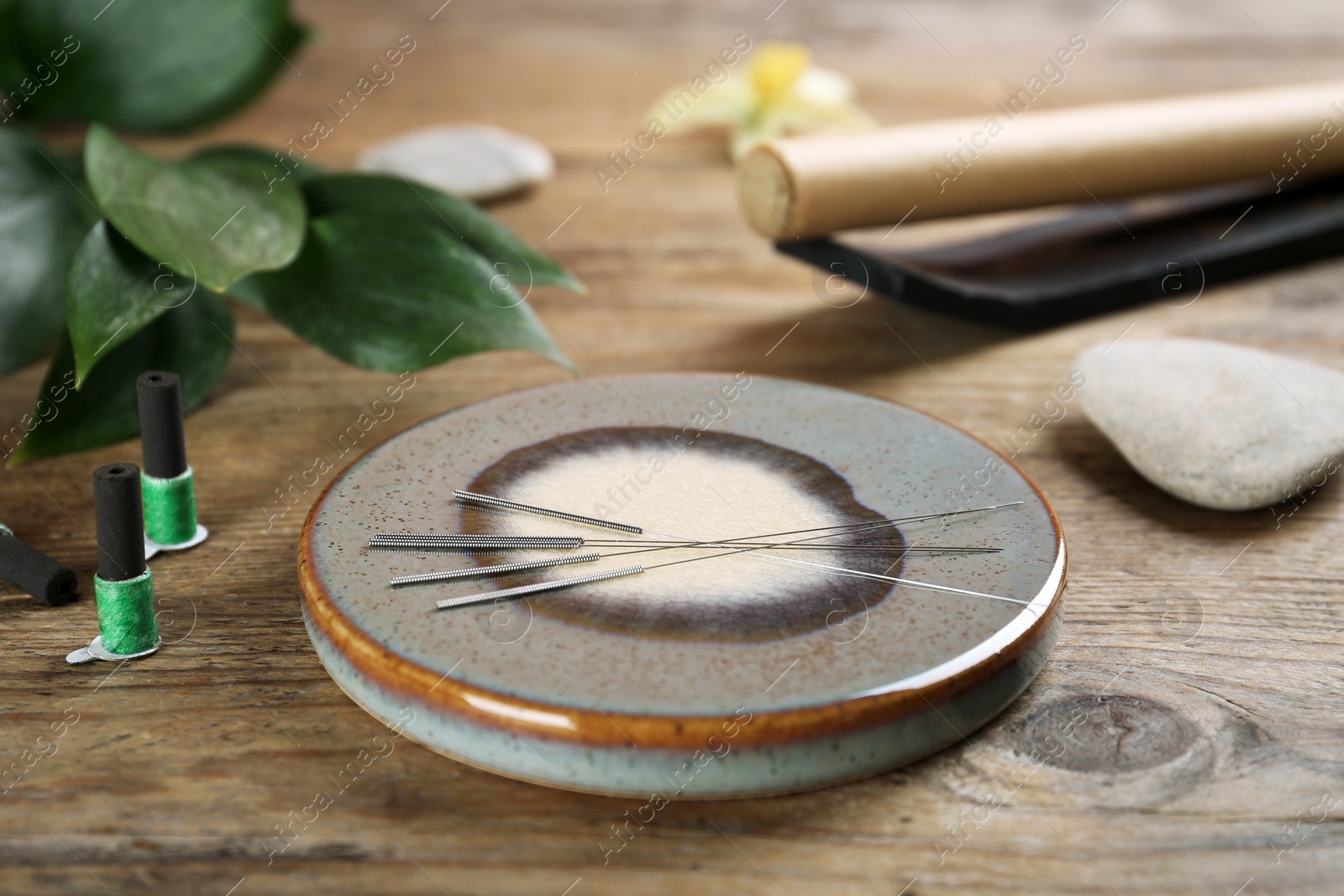 Photo of Grey stone coaster with acupuncture needles on wooden table