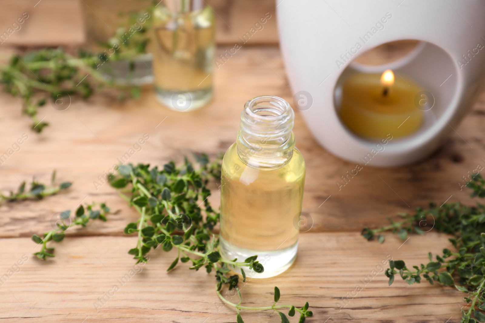 Photo of Thyme essential oil and fresh plant on wooden table, space for text