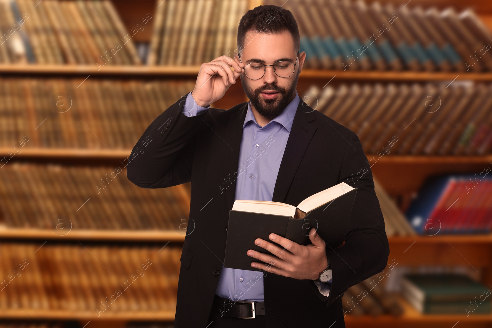 Image of Confident lawyer in glasses reading book in office