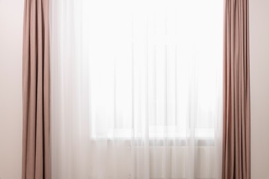 Photo of Elegant window curtains and white tulle indoors. Interior design