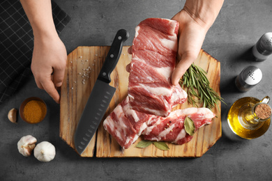 Man holding raw ribs at grey table, top view