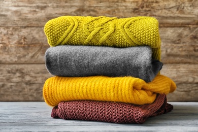 Photo of Stack of warm knitted clothes on table