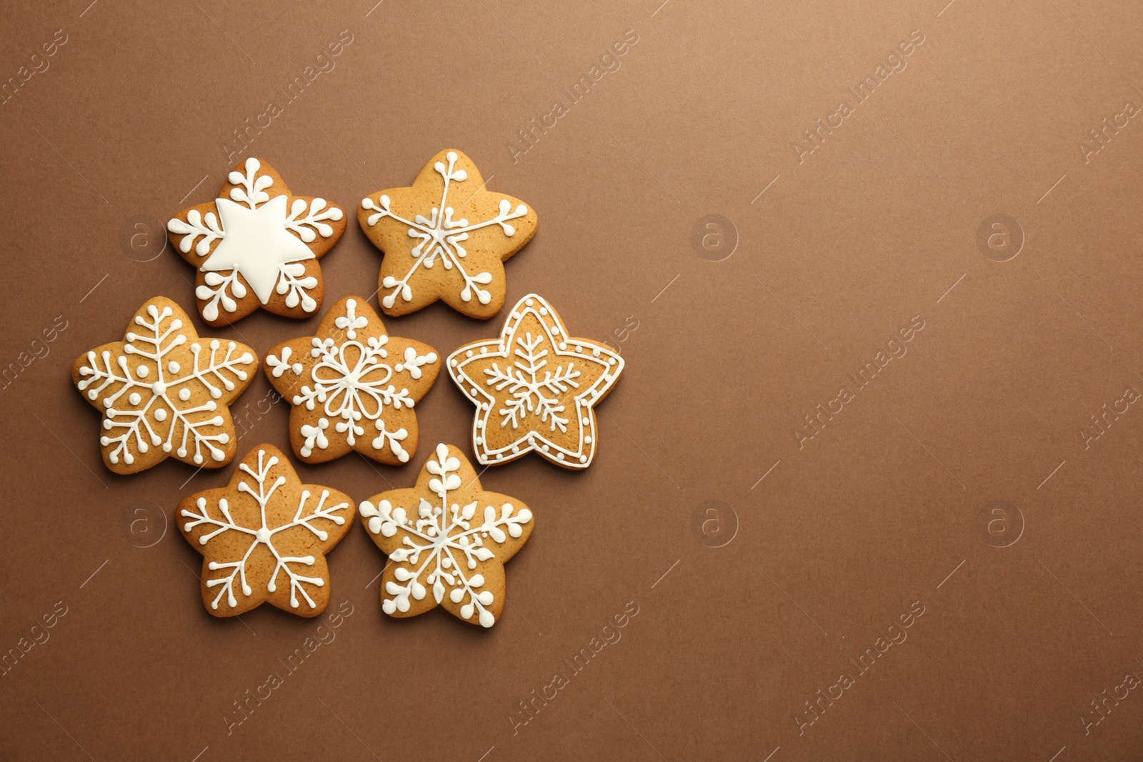 Photo of Tasty Christmas cookies with icing on brown background, flat lay. Space for text