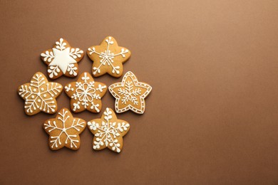 Photo of Tasty Christmas cookies with icing on brown background, flat lay. Space for text