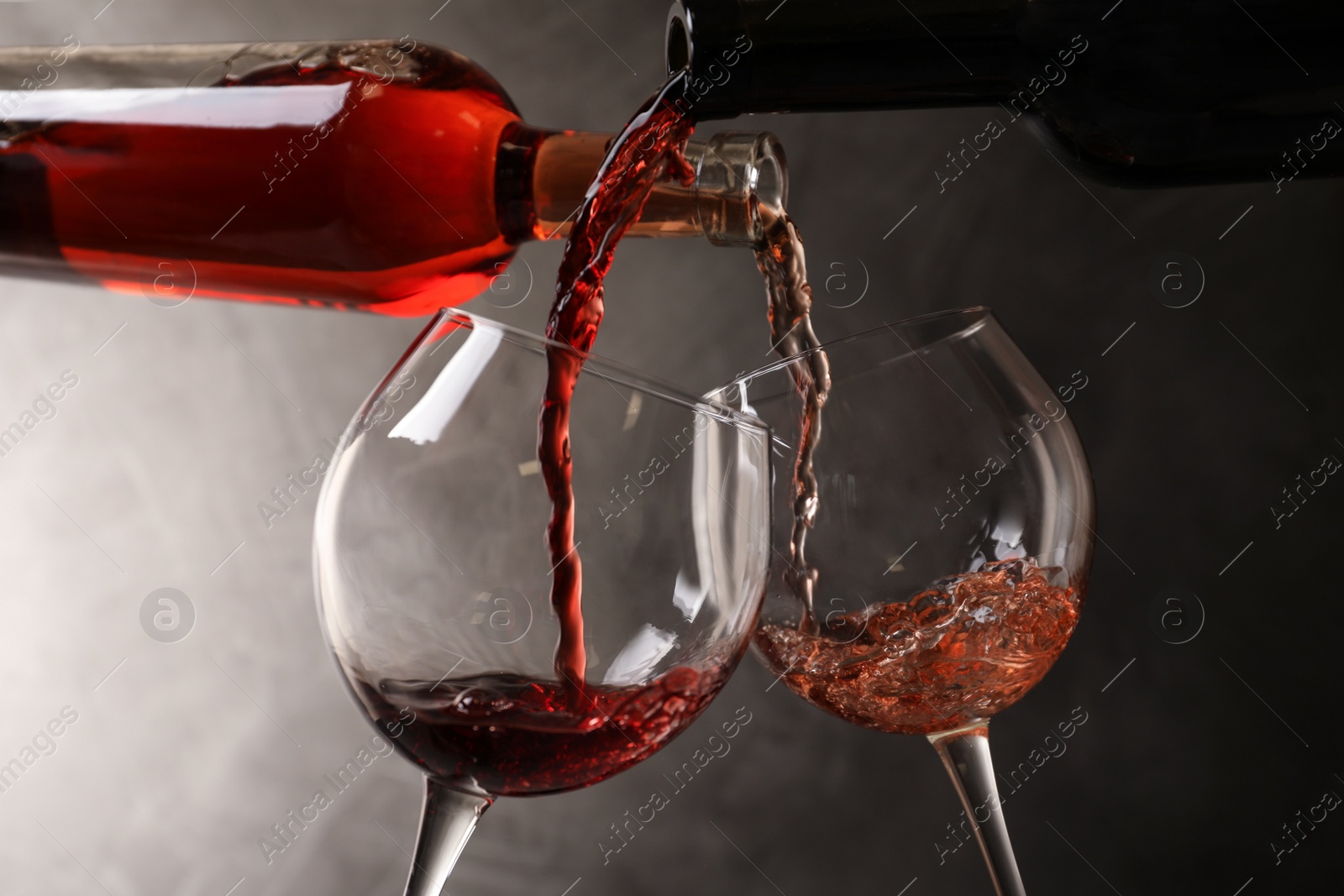 Photo of Pouring different wines from bottles into glasses on dark background