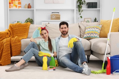 Photo of Spring cleaning. Couple with detergents and mop in living room