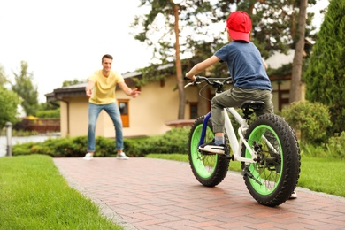 Dad teaching son to ride bicycle outdoors