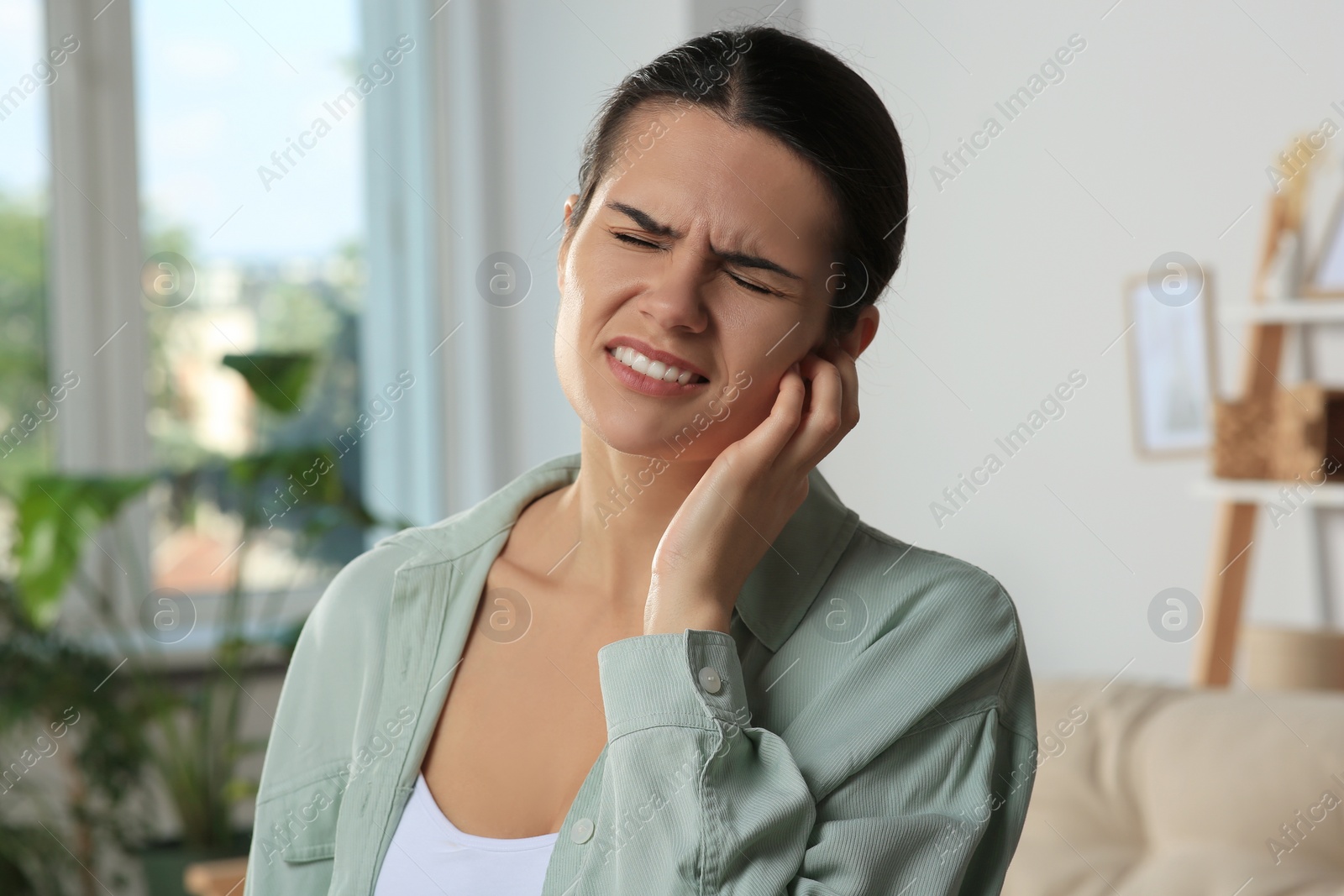 Photo of Young woman suffering from ear pain at home