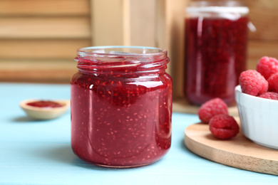 Photo of Delicious raspberry jam on light blue wooden table, closeup