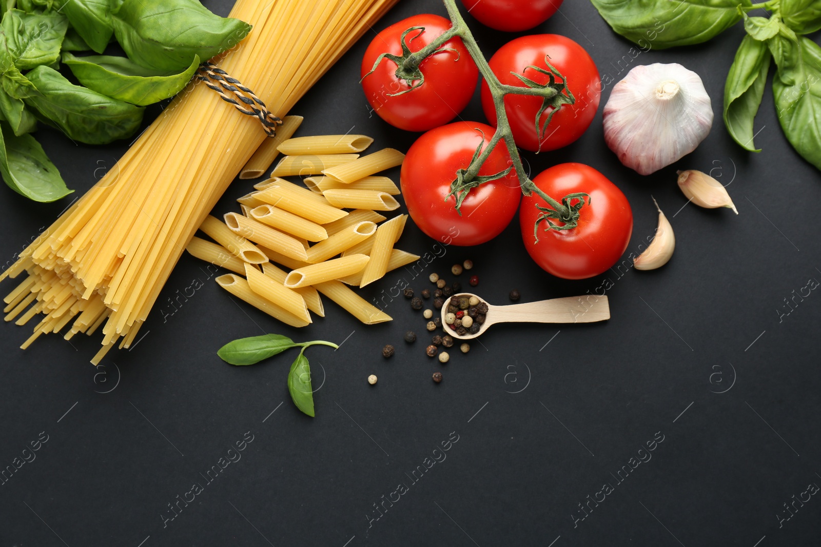 Photo of Different types of pasta, spices and products on black background, flat lay. Space for text