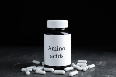 Photo of Amino acid pills and jar on grey table