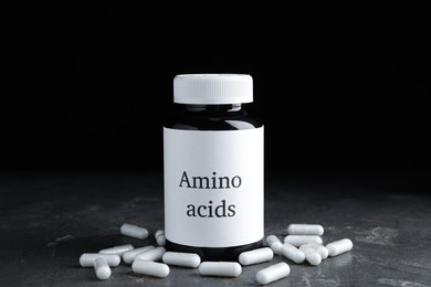 Amino acid pills and jar on grey table