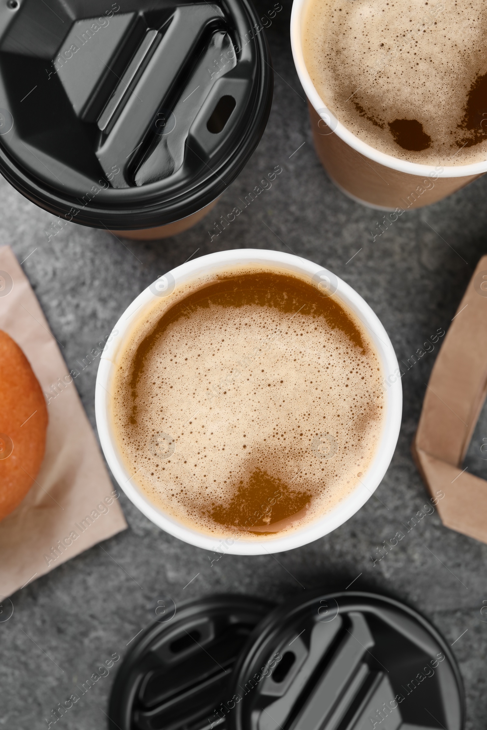 Photo of Coffee to go. Paper cups with tasty drink on grey table, flat lay