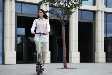 Photo of Businesswoman riding electric kick scooter on city street