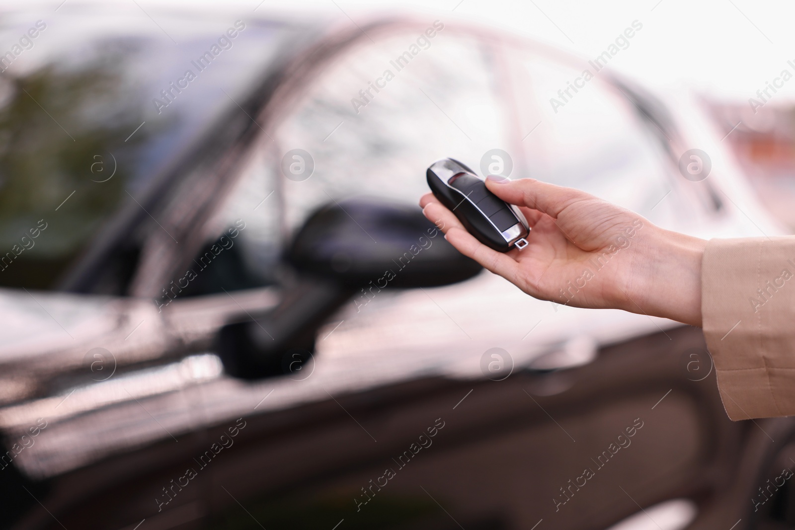 Photo of Woman holding car flip key near her vehicle outdoors, closeup