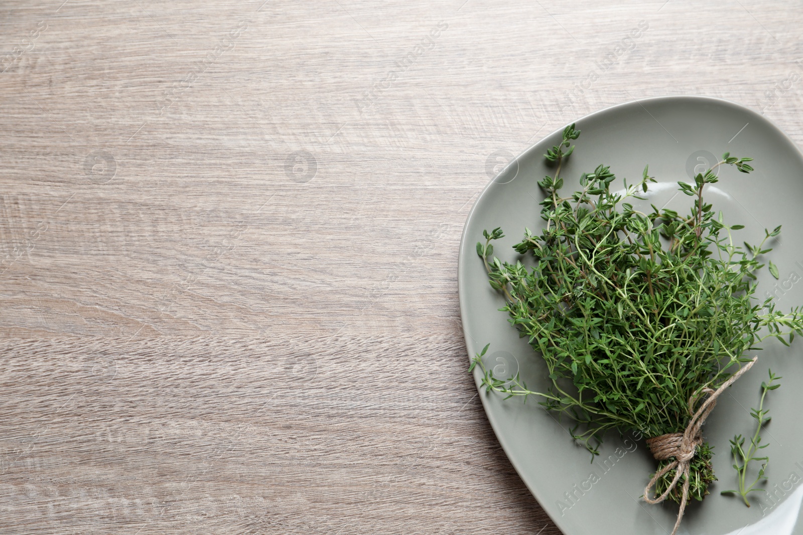 Photo of Bunch of aromatic thyme on wooden table, top view. Space for text