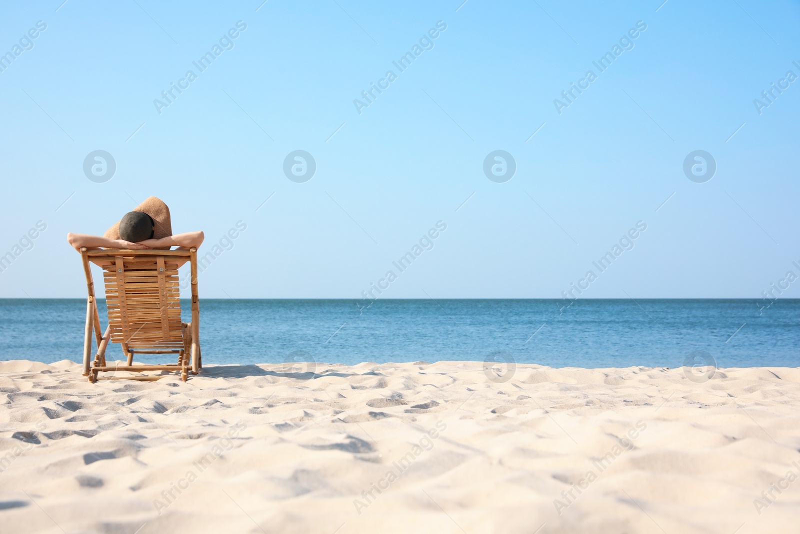 Photo of Young woman relaxing in deck chair on sandy beach