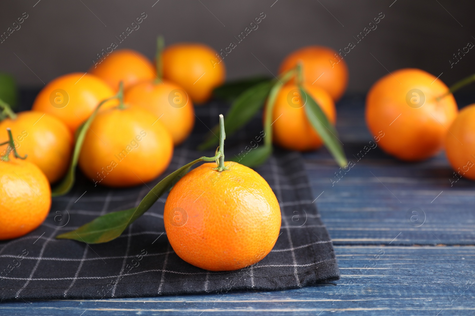 Photo of Fresh ripe tangerine on blue wooden table, closeup