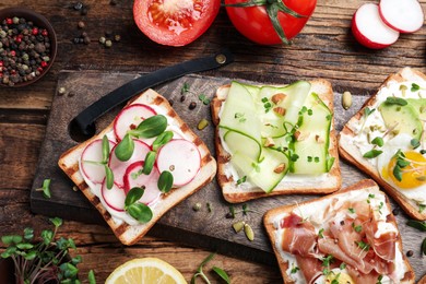 Photo of Different delicious sandwiches with microgreens on wooden table, flat lay