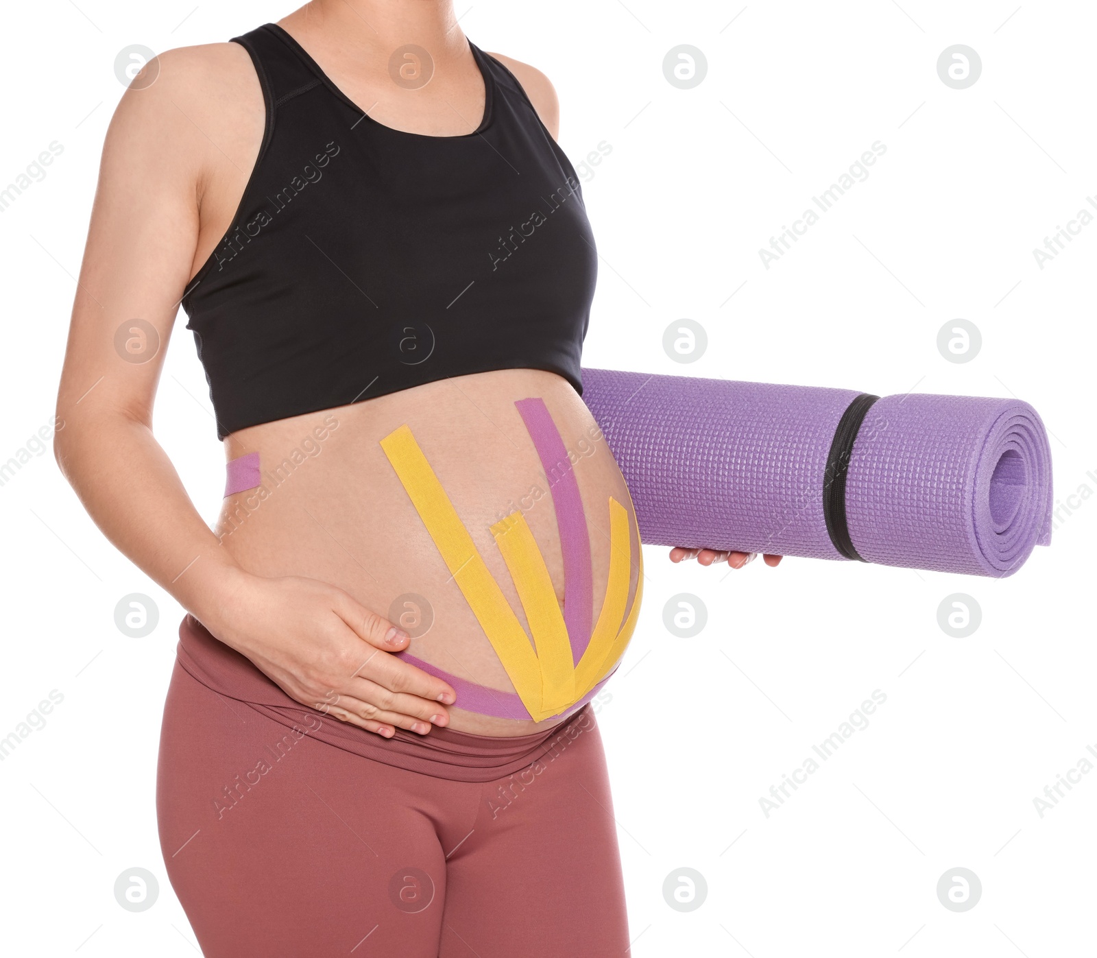 Photo of Sporty pregnant woman with kinesio tapes holding yoga mat on white background, closeup