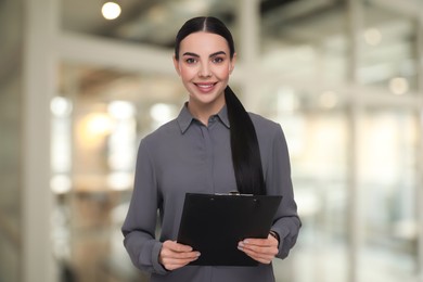 Image of Lawyer, consultant, business owner. Confident woman with clipboard smiling indoors