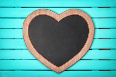 Photo of Empty heart shaped chalkboard on wooden background