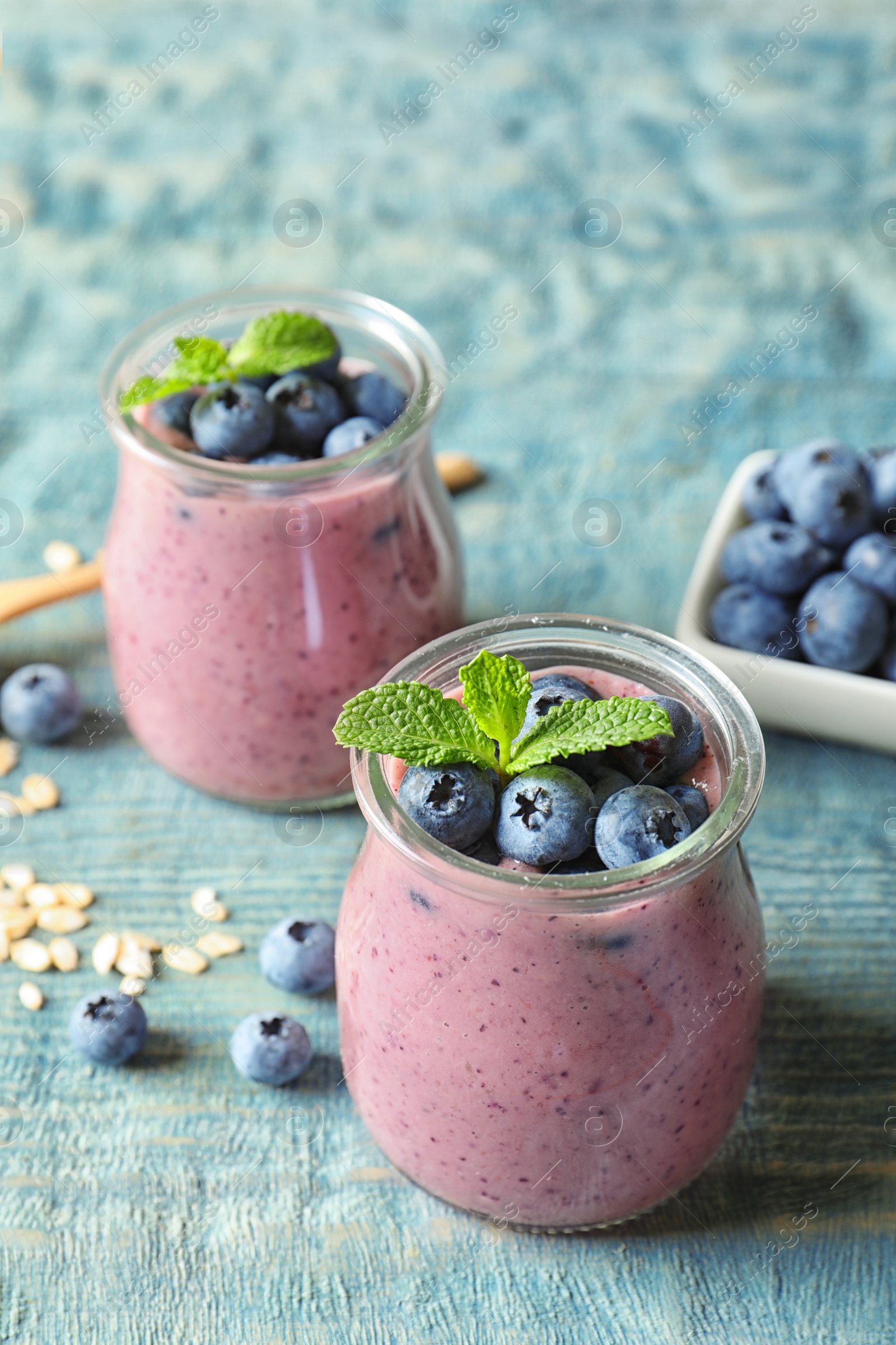 Photo of Tasty blueberry smoothie in jars and berries on wooden table