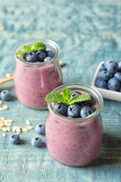 Tasty blueberry smoothie in jars and berries on wooden table