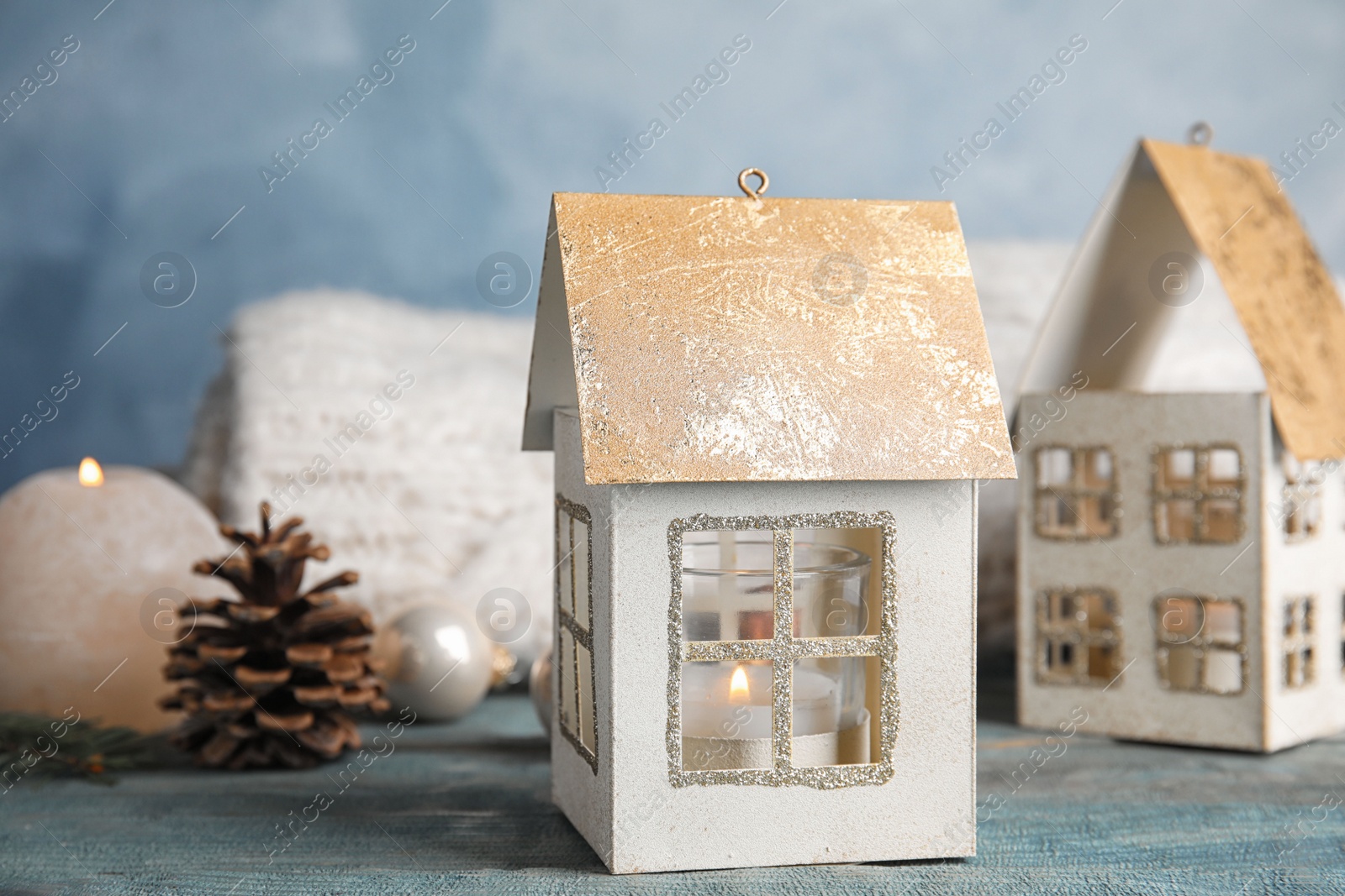 Photo of Composition with candle in house shaped holder on blue wooden table. Christmas decoration