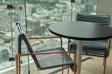 Coffee table and chairs against picturesque landscape of city in cafe