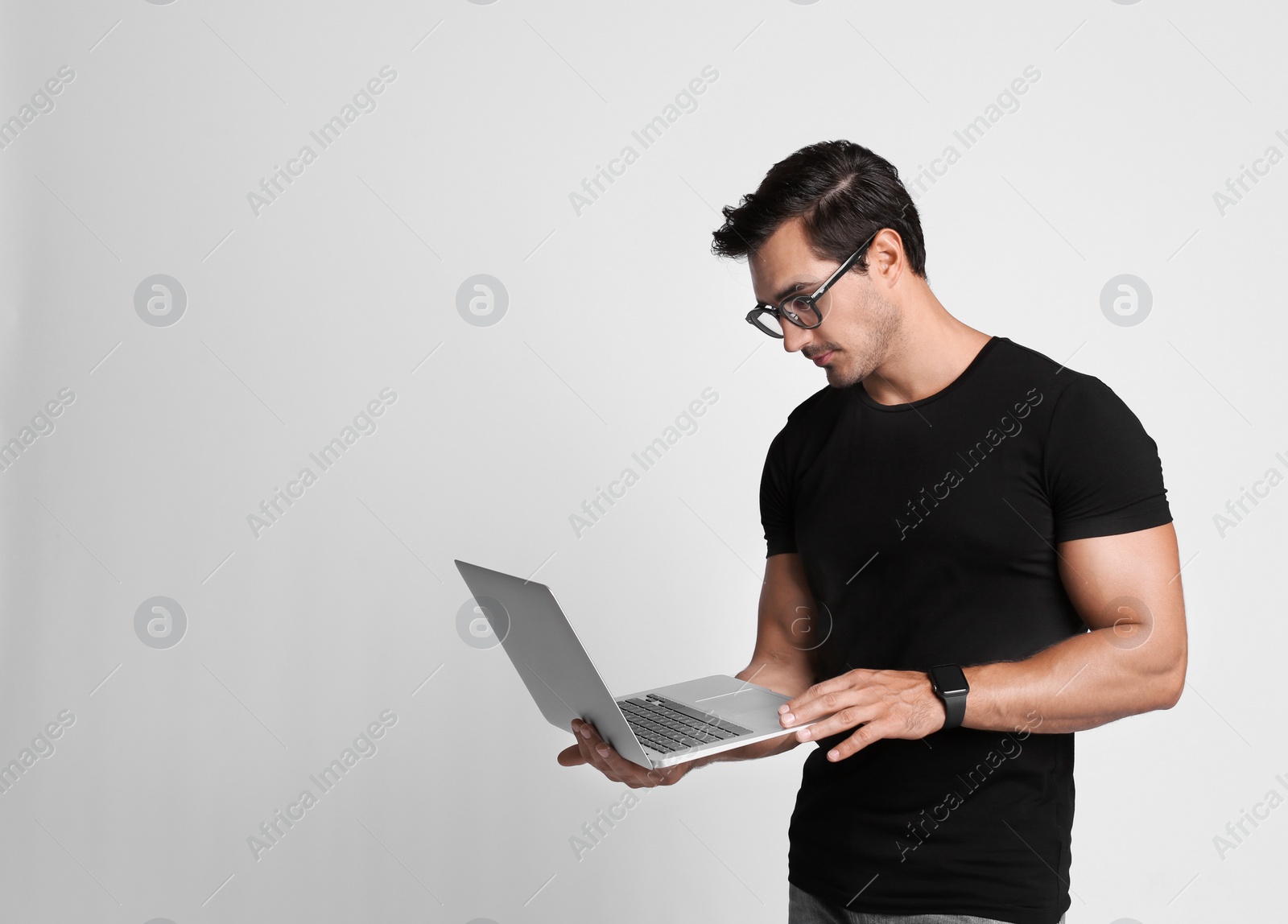 Photo of Handsome young man with laptop on grey background. Space for text