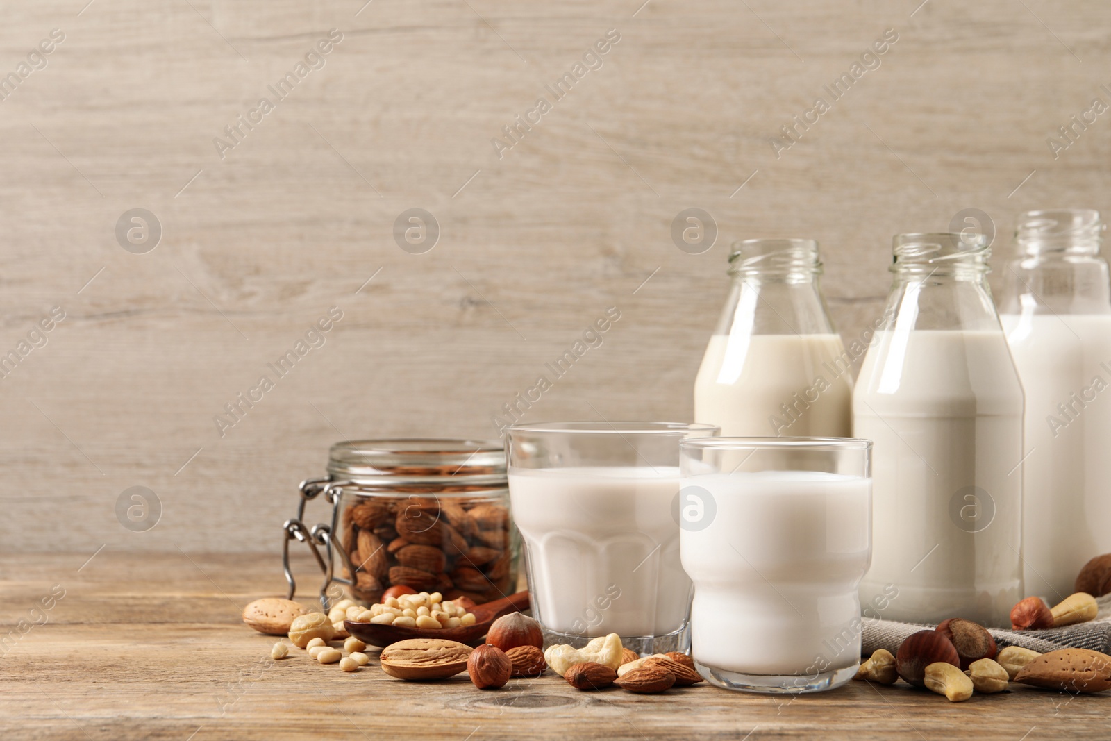 Photo of Different nut milks on wooden table. Space for text