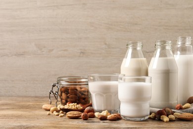 Different nut milks on wooden table. Space for text