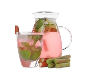 Photo of Glass and jug of tasty rhubarb cocktail with stems isolated on white