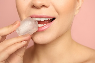 Young woman with ice cube on color background, closeup