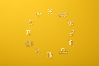 Photo of Zodiac signs on yellow background, flat lay. Space for text