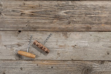 Different corkscrews on wooden table, flat lay. Space for text