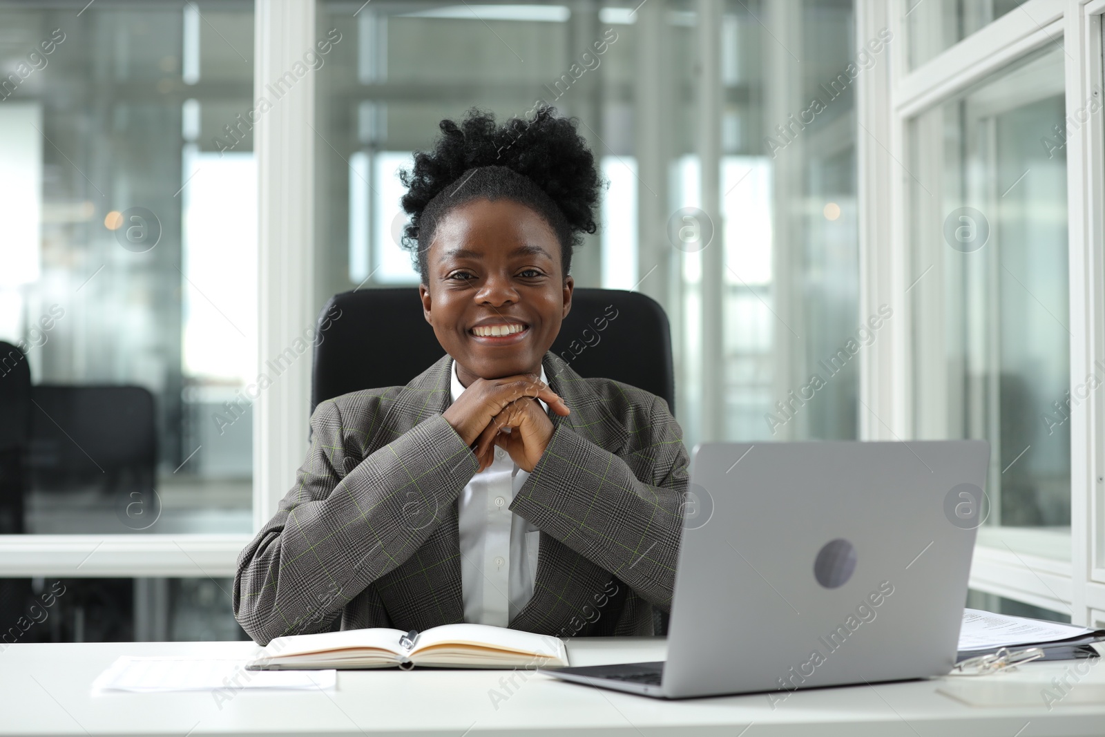 Photo of Happy woman working at table in office. Lawyer, businesswoman, accountant or manager