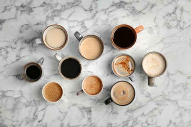 Photo of Many cups of different aromatic hot coffee on marble table