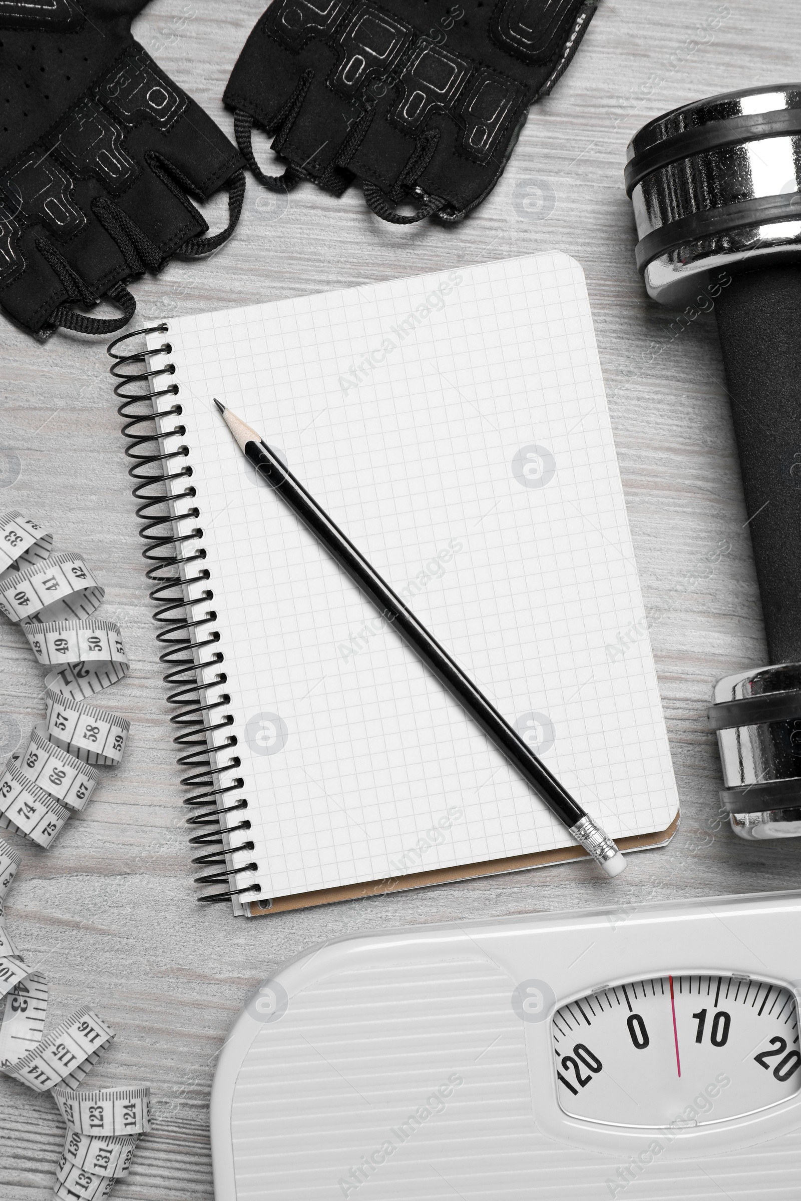 Photo of Notebook, scales and sports equipment on white wooden table, flat lay. Personal training