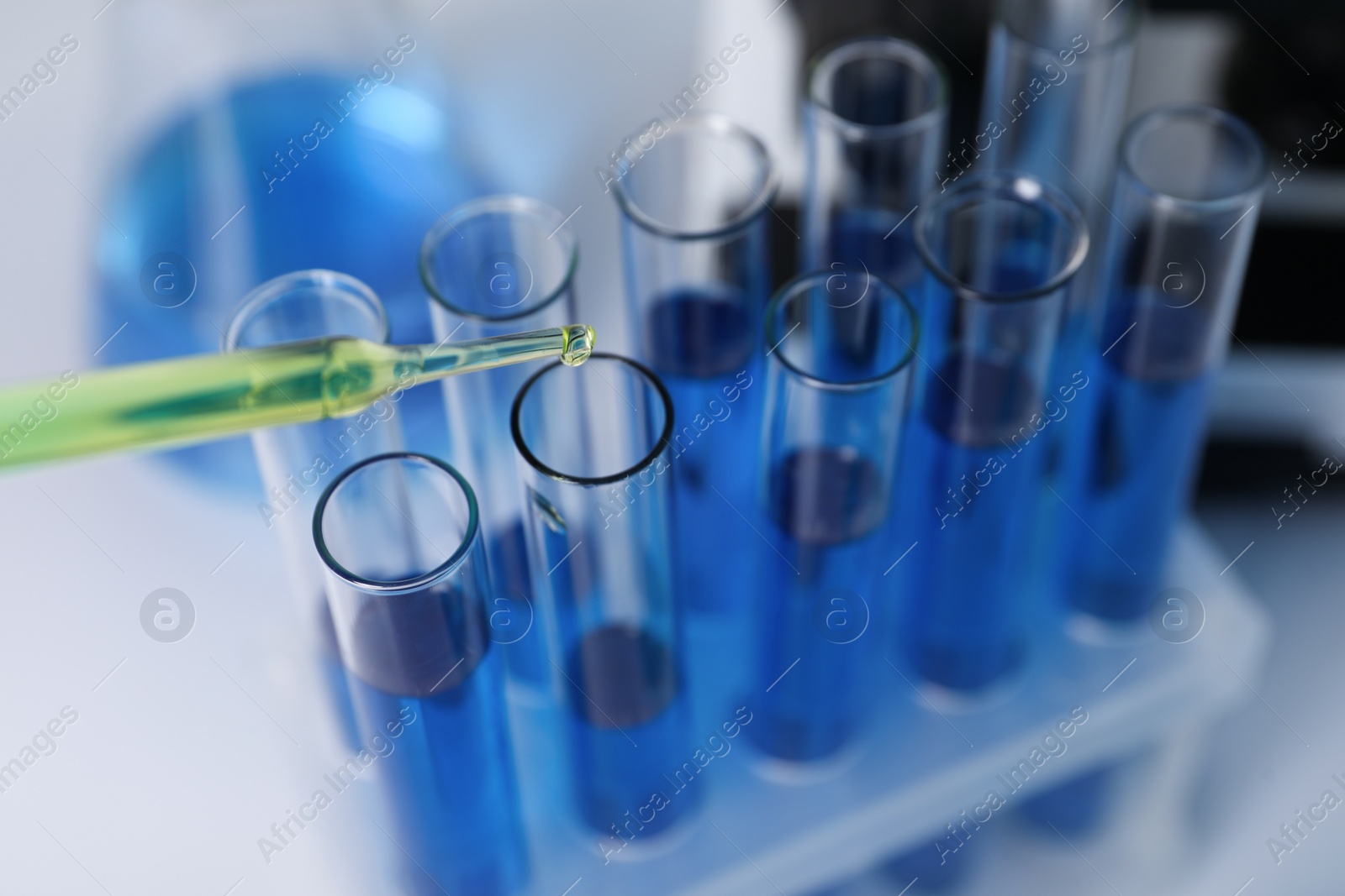 Photo of Laboratory analysis. Dripping liquid into test tubes on white table, closeup