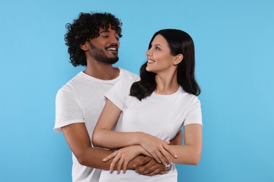 Photo of International dating. Happy couple hugging on light blue background