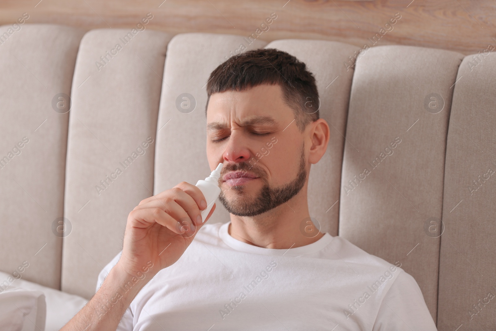 Photo of Ill man using nasal spray in bed at home