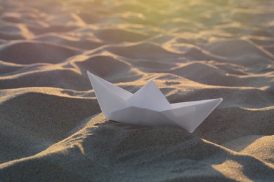 Photo of Beautiful white paper boat on sand outdoors