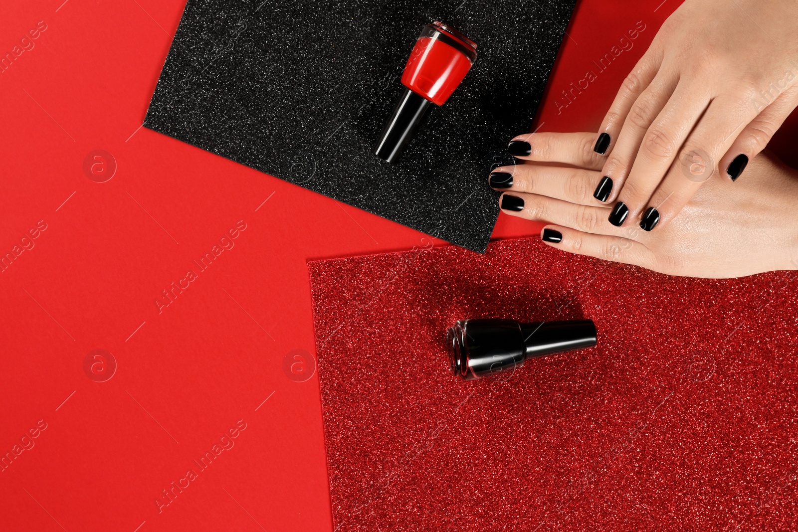 Photo of Woman with black manicure and nail polish bottles on color background, top view. Space for text