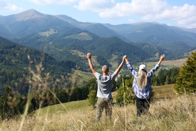 Couple enjoying picturesque mountain landscape, back view. Space for text