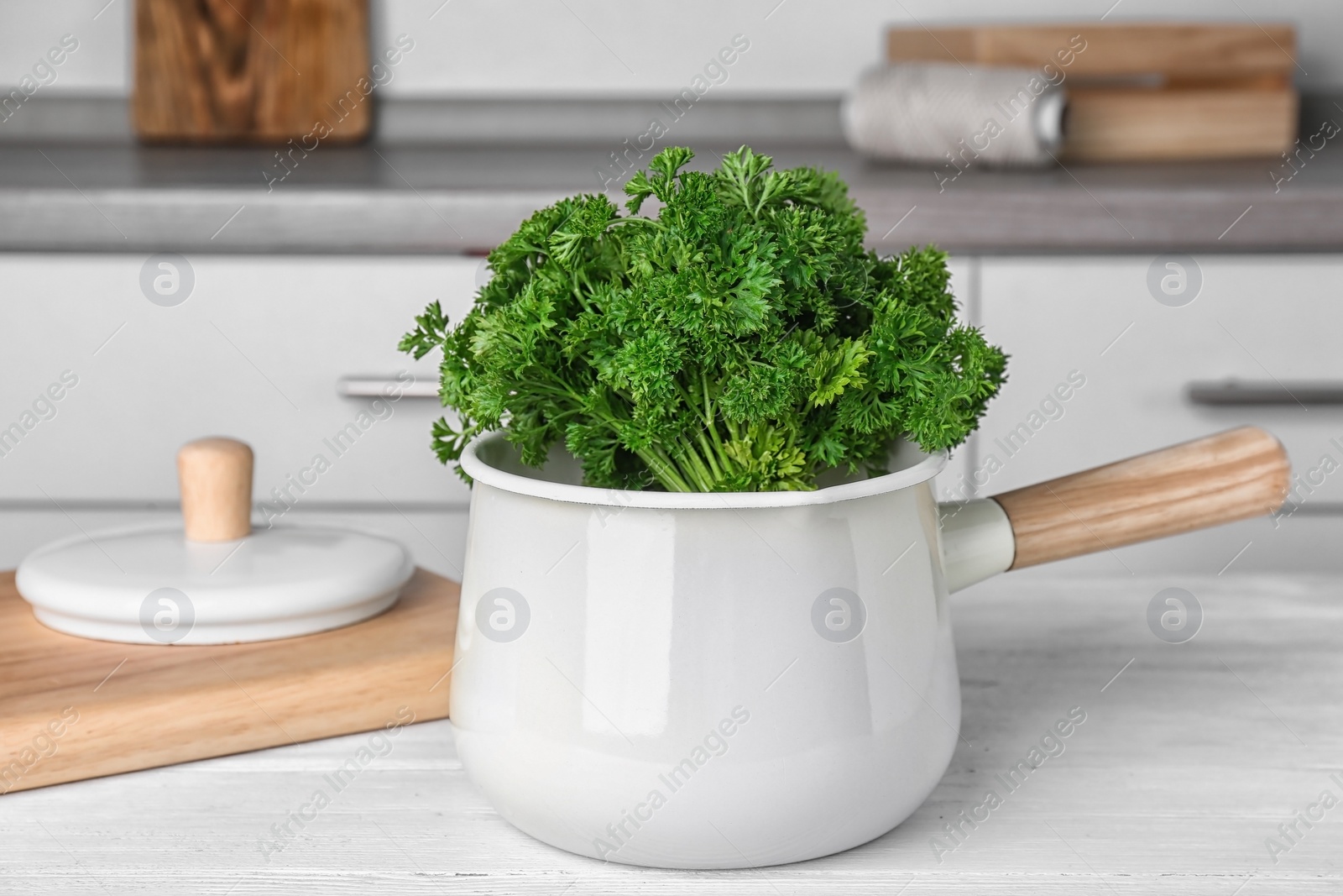 Photo of Saucepan with fresh green parsley on table