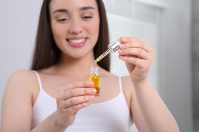 Photo of Young woman with essential oil in bathroom, selective focus