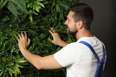 Man installing green artificial plant panel on grey wall