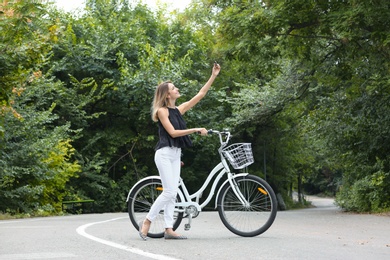 Attractive woman taking selfie near bicycle outdoors